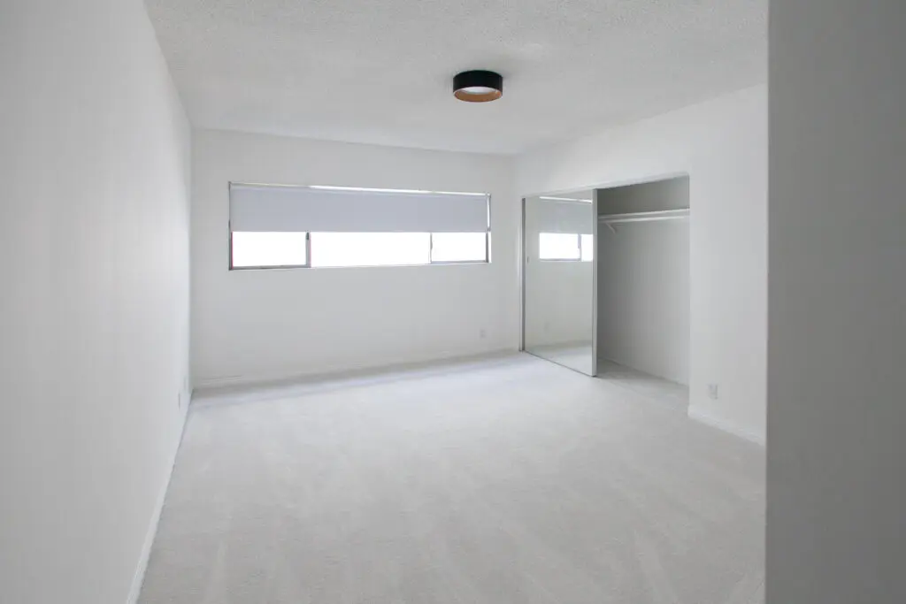 Empty white room with window and closet.