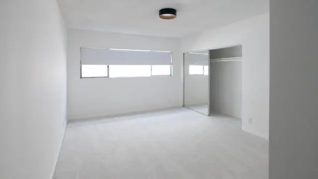 Empty white room with window and closet.