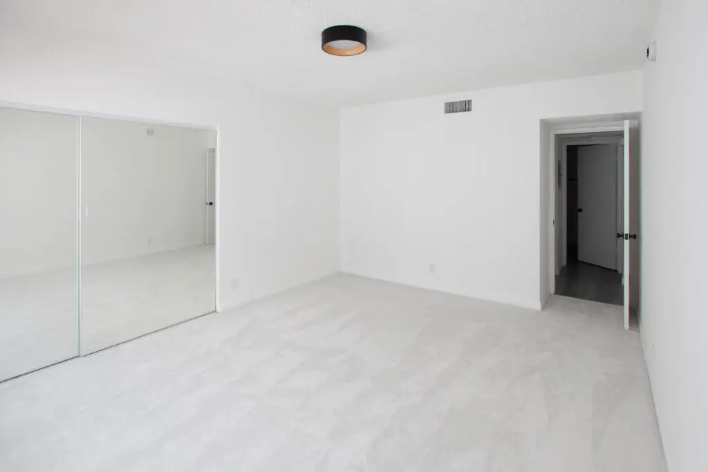 Empty white room with mirrored closet doors.