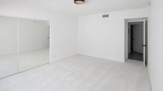 Empty white room with mirrored closet doors.
