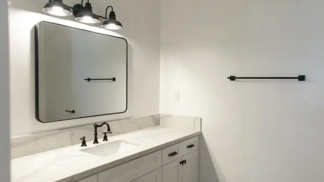 Modern bathroom with white cabinets and mirror.