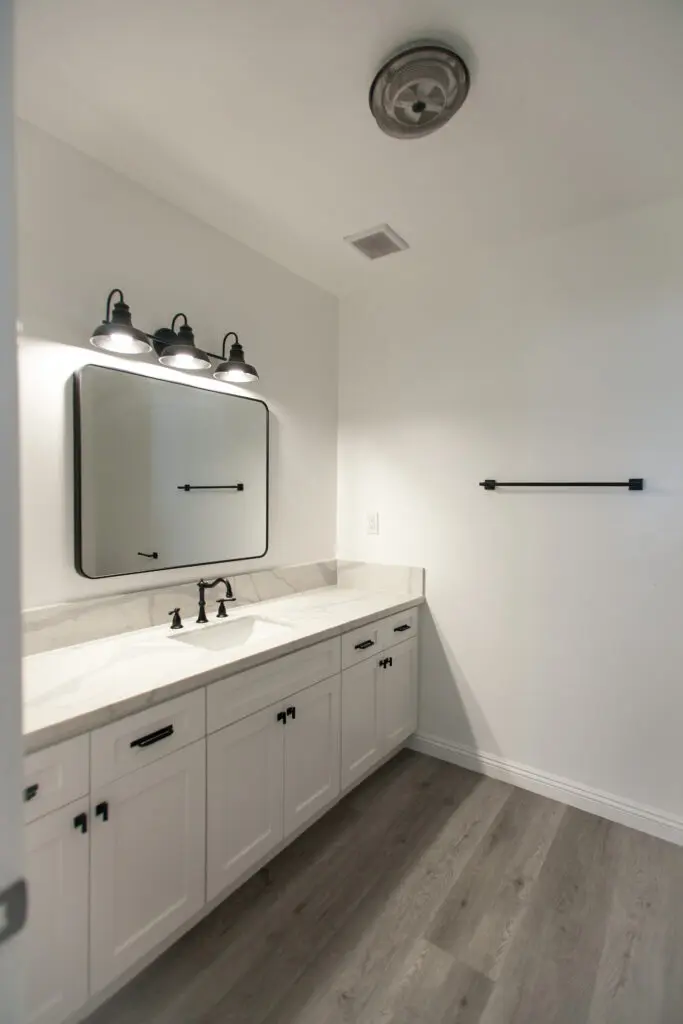 Modern bathroom with white cabinets and mirror.