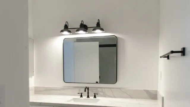 Modern bathroom vanity with mirror and lights.